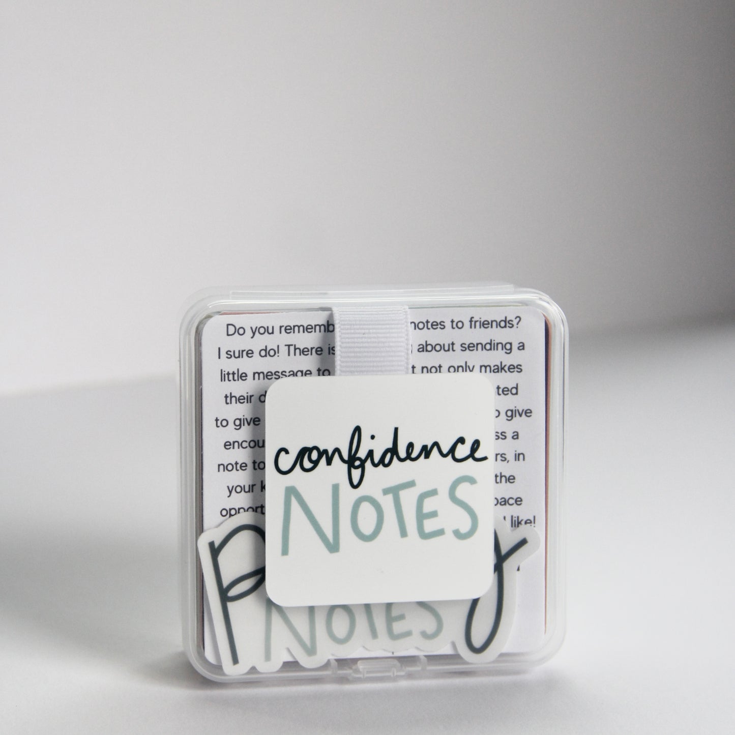 A small clear plastic box labeled "Confidence Notes" holds handwritten text and inspirational note cards inside.