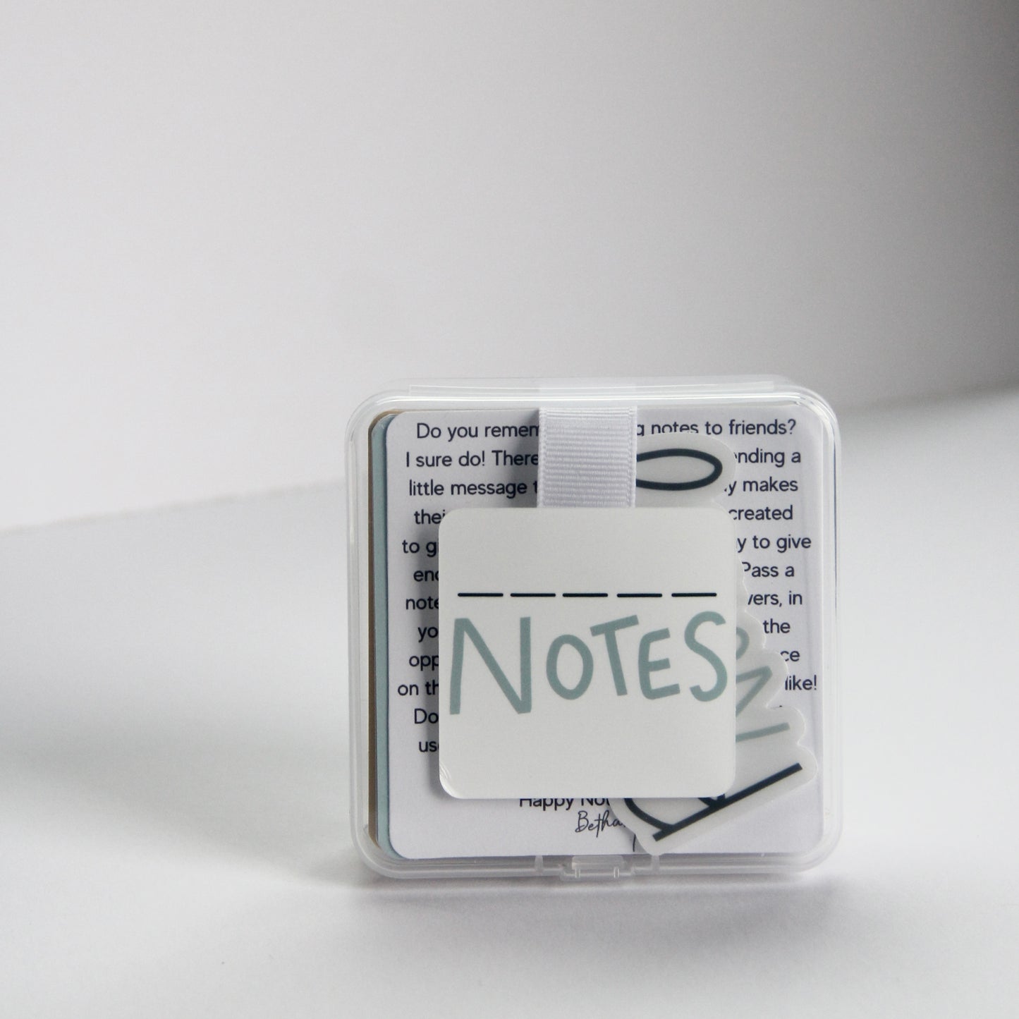 A small clear plastic case with a white square label reading "Fill in the Blank Notes" in a playful font. The box contains 40 durable note cards that include encouraging prompts that you can fill out and pass on to others for a boost of appreciation and encouragement!