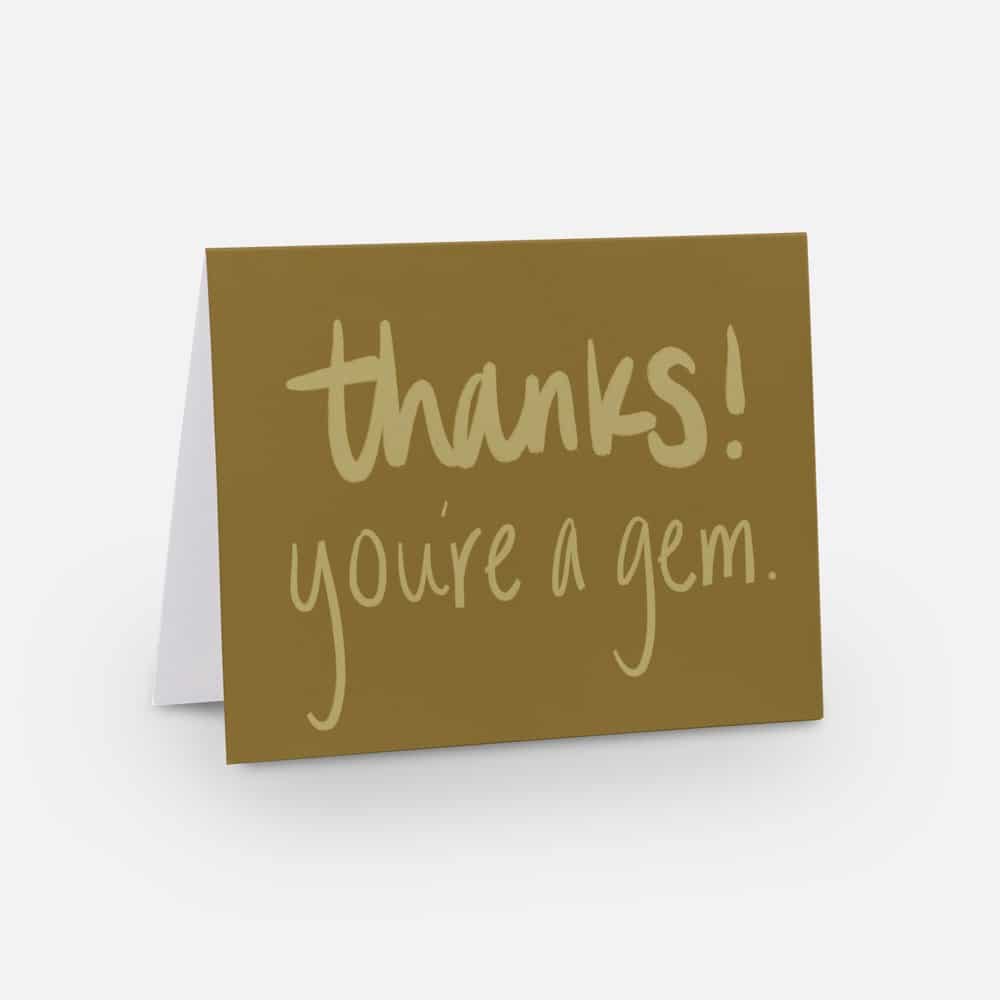 A thank you card with a brown cover features the handwritten message "thanks! you're a gem." This artful keepsake is perfect for expressing gratitude and is propped open against a plain background.