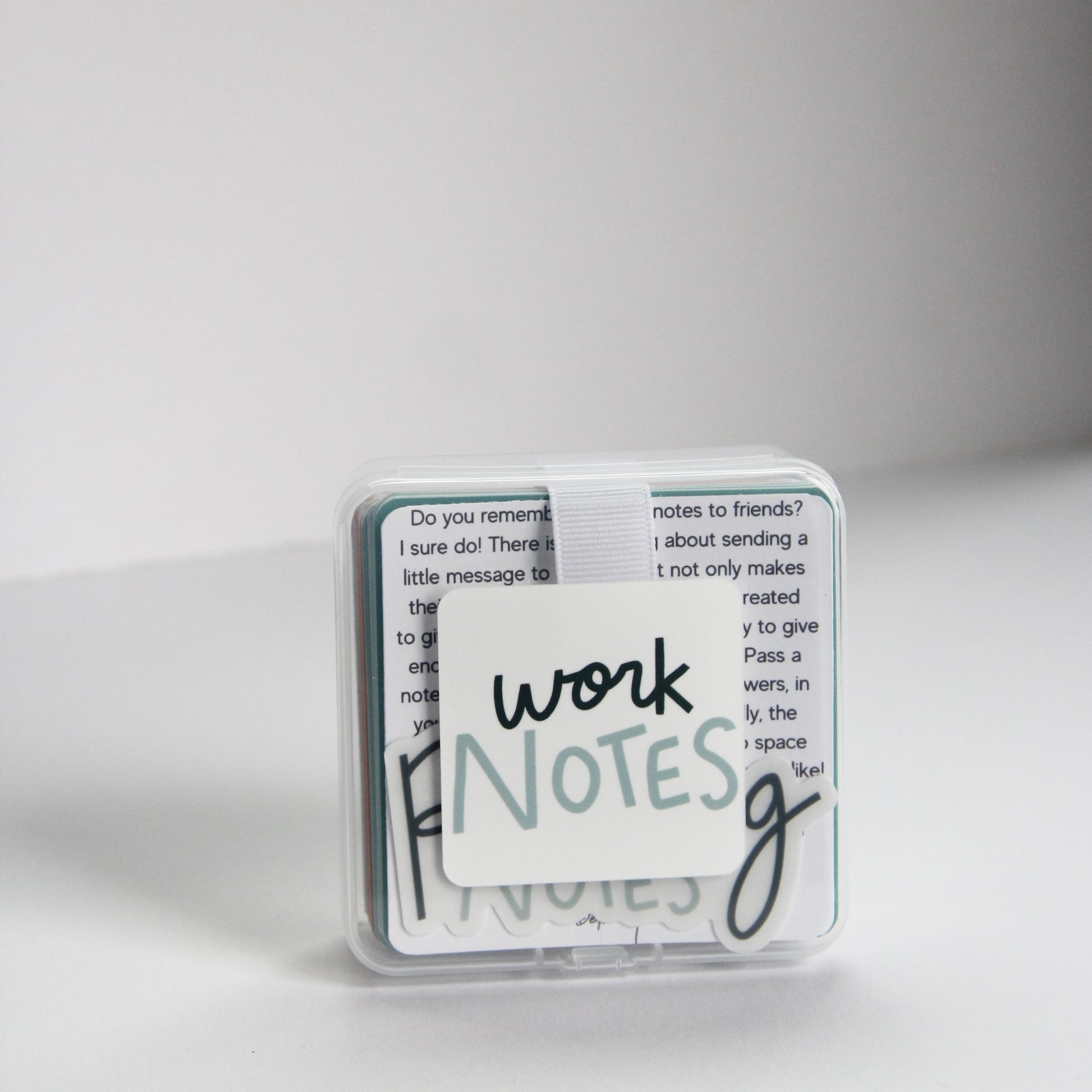 A small, transparent case with a stack of note cards inside. The top card features the words "work notes" in black and blue handwritten text. Perfect for passing notes of appreciation to coworkers.