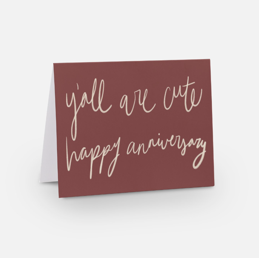 A greeting card on a white background features the "Y'all are Cute" design with the text "happy anniversary" in elegant cursive on a burgundy cover, perfect for celebrating special moments.