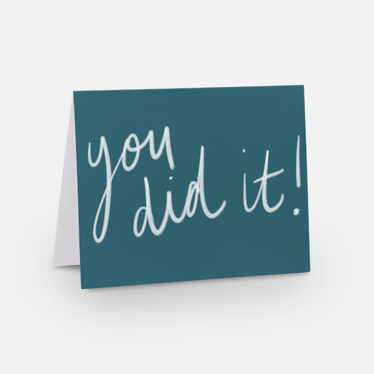 A2 horizontal sized card with a rich medium blue background with a white handwritten font that says "you did it!"