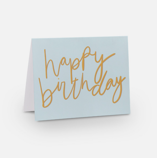 A2 horizontal sized card with light blue background and a golden handwritten font that has a red underlay to give it a pop, and it reads "happy birthday"